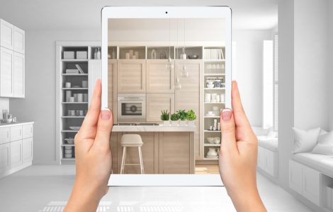 Mains tenant une tablette montrant une cuisine moderne blanche et en bois