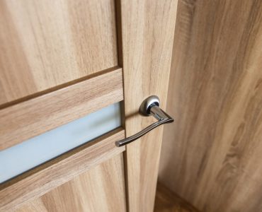 Zoom sur les détails d’une porte en bois clair et sa poignée chromée