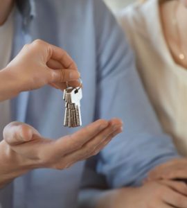 Un agent immobilier donne les clés d’une maison à un jeune couple