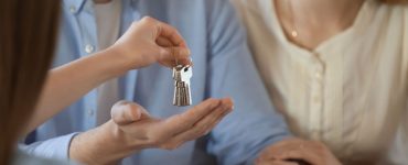 Un agent immobilier donne les clés d’une maison à un jeune couple