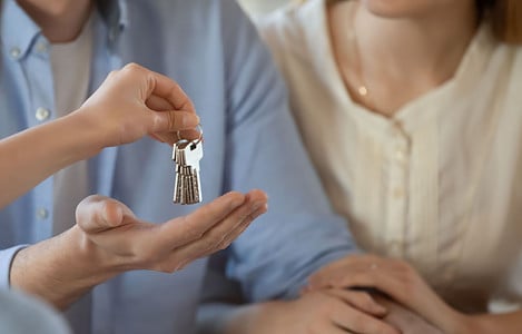 Un agent immobilier donne les clés d’une maison à un jeune couple