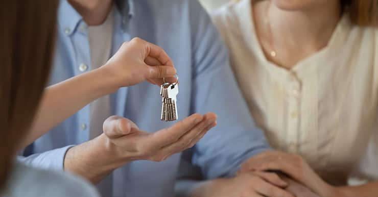 Un agent immobilier donne les clés d’une maison à un jeune couple