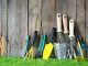 Différents outils de jardin posés sur une pelouse verte et un mur en bois