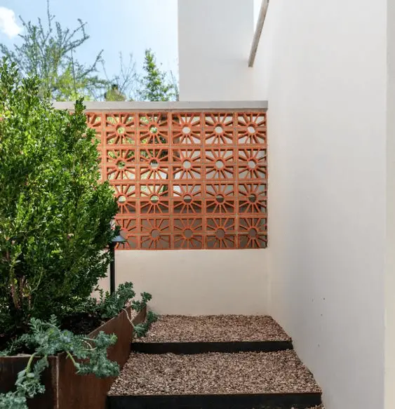 Des breeze block en terre cuite sur un muret en béton blanc