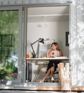 Vue sur une femme assise dans une petite maison en container