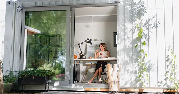 Vue sur une femme assise dans une petite maison en container