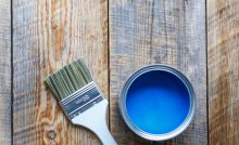 Pot de peinture bleu ouvert avec un pinceau neuf posé à côté
