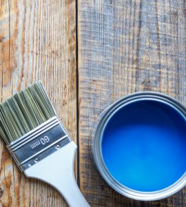 Pot de peinture bleu ouvert avec un pinceau neuf posé à côté