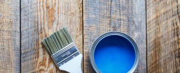 Pot de peinture bleu ouvert avec un pinceau neuf posé à côté