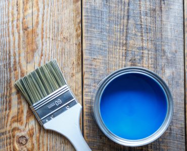 Pot de peinture bleu ouvert avec un pinceau neuf posé à côté