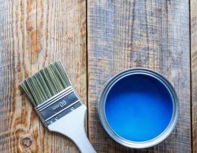 Pot de peinture bleu ouvert avec un pinceau neuf posé à côté