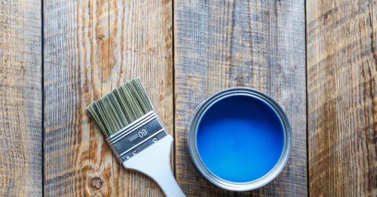 Pot de peinture bleu ouvert avec un pinceau neuf posé à côté