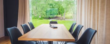 Table à manger en bois avec vue sur l'extérieur à travers une grande baie vitrée