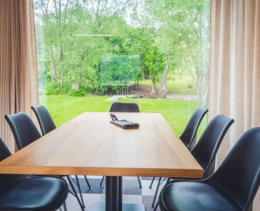 Table à manger en bois avec vue sur l'extérieur à travers une grande baie vitrée