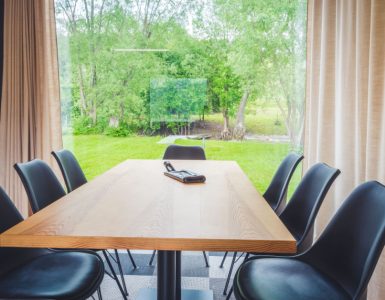 Table à manger en bois avec vue sur l'extérieur à travers une grande baie vitrée