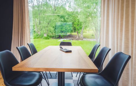 Table à manger en bois avec vue sur l'extérieur à travers une grande baie vitrée