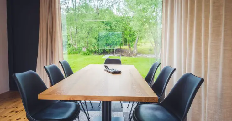 Table à manger en bois avec vue sur l'extérieur à travers une grande baie vitrée