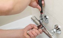 Un homme utilise une clé pour resserrer le mitigeur de la salle de bain