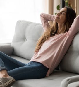 Une jeune femme sereine assise confortablement sur son canapé