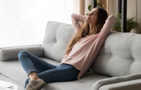 Une jeune femme sereine assise confortablement sur son canapé