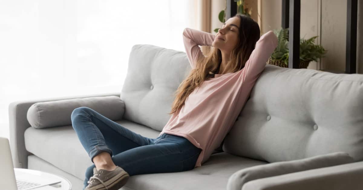 Une jeune femme sereine assise confortablement sur son canapé