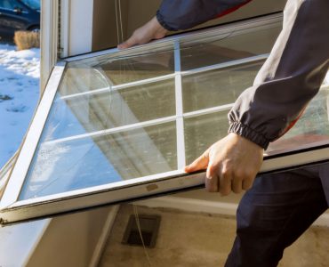 Un homme en train de remplacer une fenêtre de sa maison