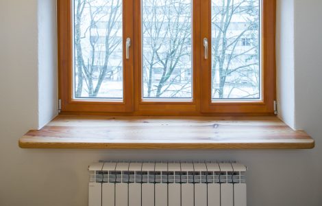 Un radiateur de chauffage placé sous une fenêtre en bois