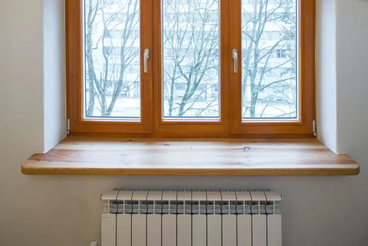 Un radiateur de chauffage placé sous une fenêtre en bois