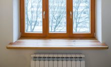 Un radiateur de chauffage placé sous une fenêtre en bois