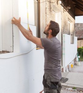 Un homme en train d’installer l'isolation thermique de la façade