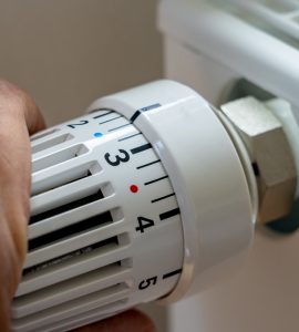 Gros plan sur la main d'un homme régulant la température avec le thermostat