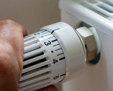 Gros plan sur la main d'un homme régulant la température avec le thermostat