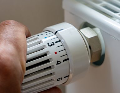 Gros plan sur la main d'un homme régulant la température avec le thermostat