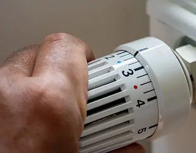 Gros plan sur la main d'un homme régulant la température avec le thermostat