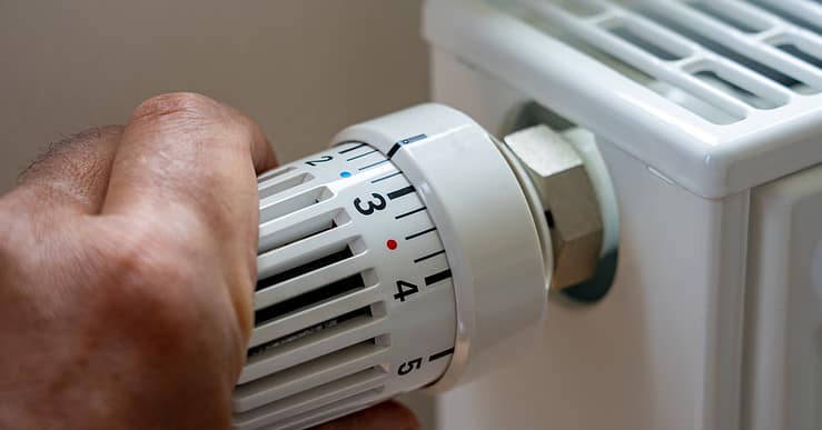 Gros plan sur la main d'un homme régulant la température avec le thermostat