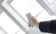 Une personne ouvre les fenêtres du toit d'une maison à l'aide d'une télécommande