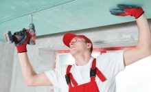 Un homme en combinaison fixe un plafond suspendu