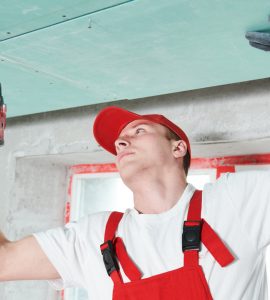 Un homme en combinaison fixe un plafond suspendu