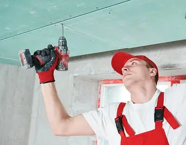 Un homme en combinaison fixe un plafond suspendu