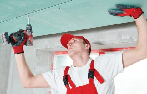 Un homme en combinaison fixe un plafond suspendu