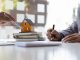 Deux hommes d'affaires signant un contrat avec une petite maquette de maison en fond
