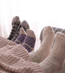 3 personnes dans le lit se réchauffent en tendant leurs pieds vers le radiateur