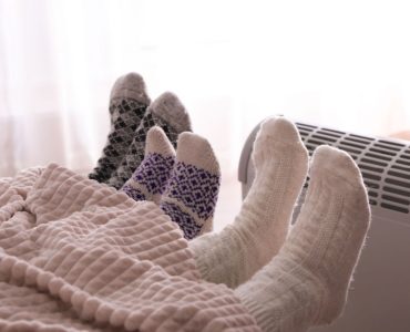 3 personnes dans le lit se réchauffent en tendant leurs pieds vers le radiateur