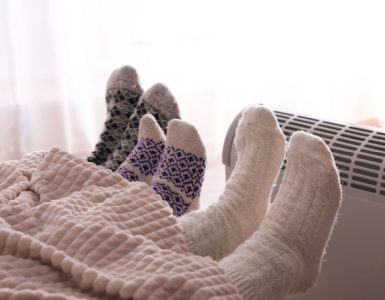 3 personnes dans le lit se réchauffent en tendant leurs pieds vers le radiateur