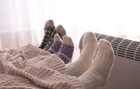 3 personnes dans le lit se réchauffent en tendant leurs pieds vers le radiateur