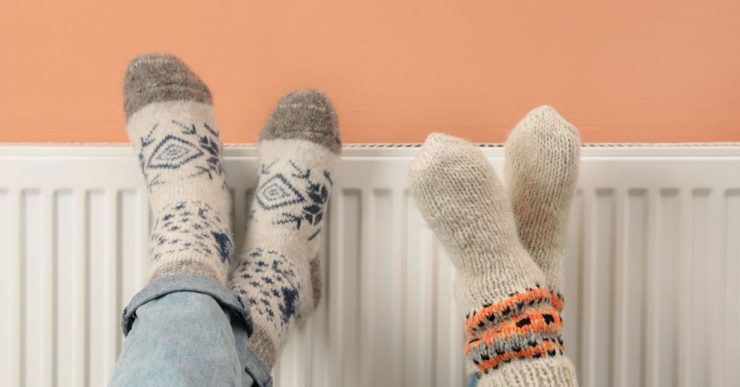 Deux personnes croisent les jambes sur le chauffage de la maison