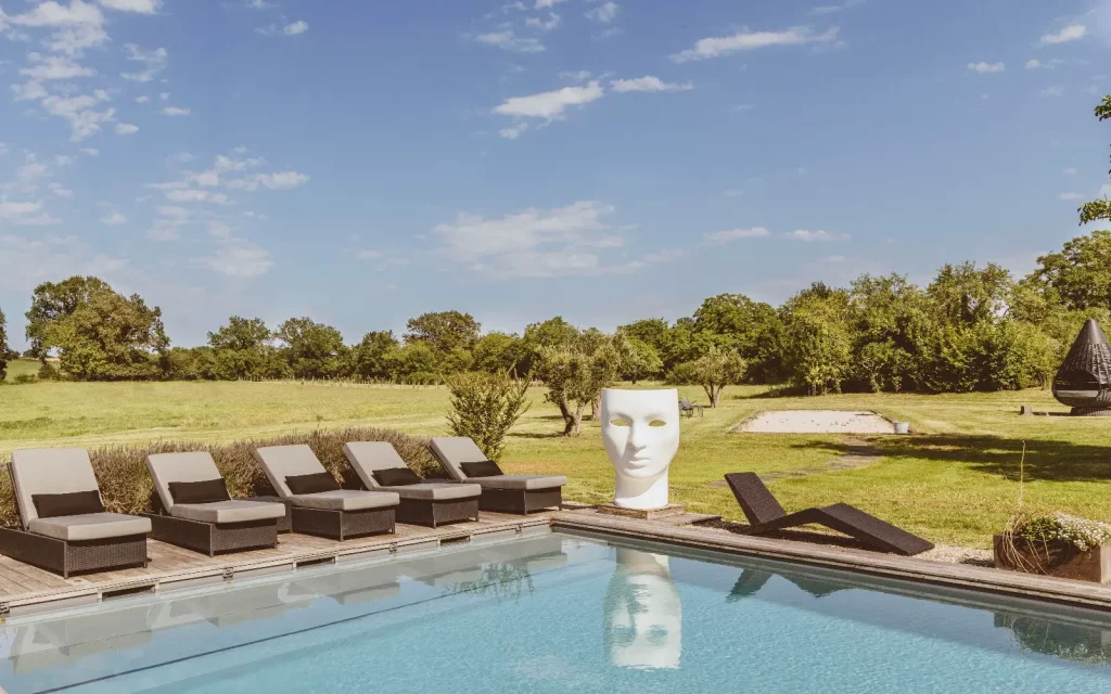 une grande piscine entourée de transats dans le jardin