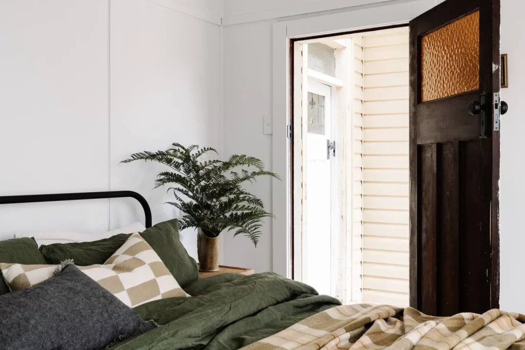 une chambre double et son lit en métal près d'une porte en bois