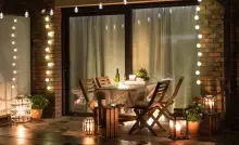 Une table à manger dressée sur la terrasse avec plusieurs lampes et ampoules allumées