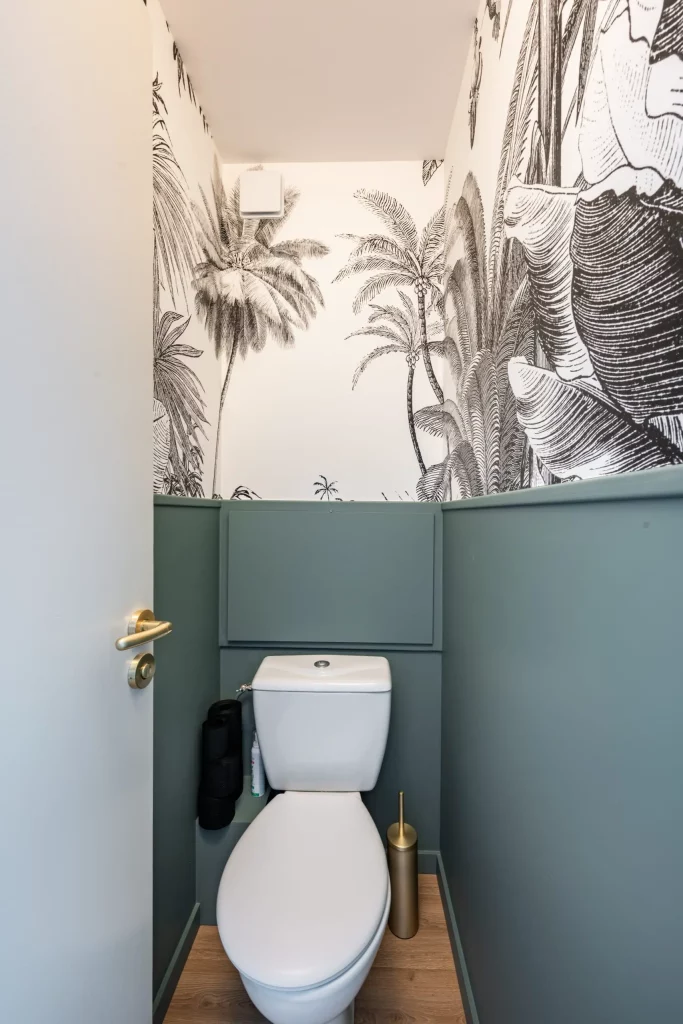 des toilettes avec un peau papier peint et un mur vert